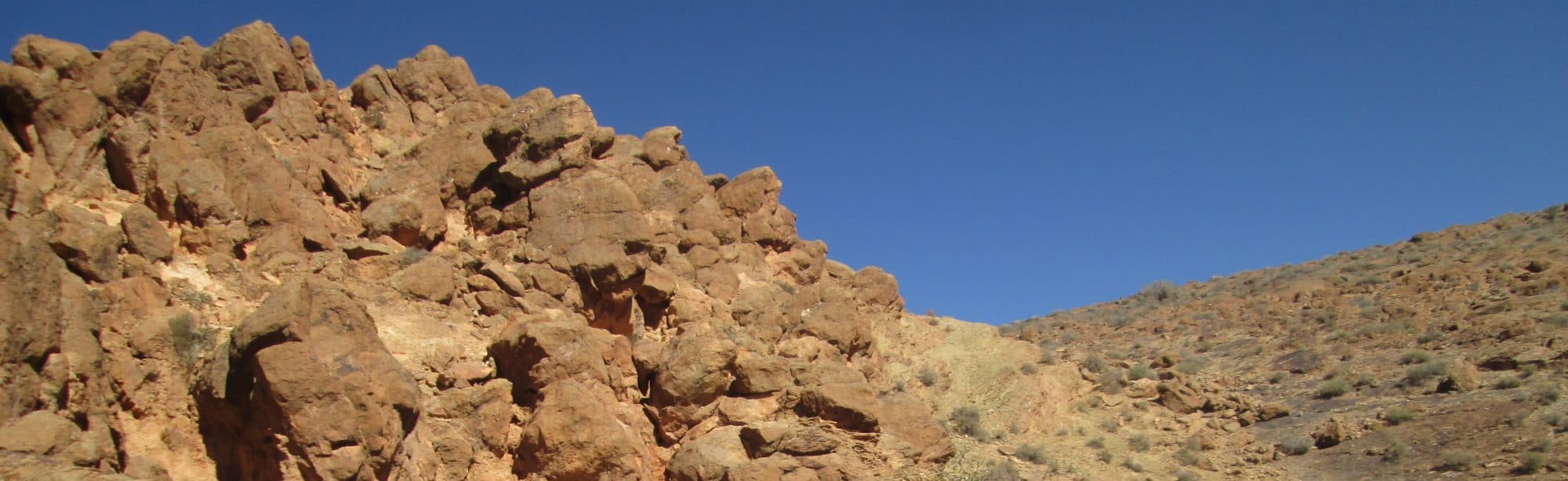 Rocky desert hillside under a blue sky